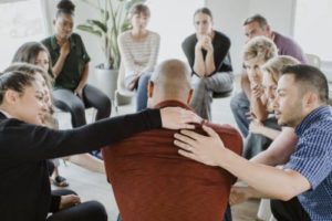 people consoling bald man in group treatment after he opened up about he profound cocain Addiciton 