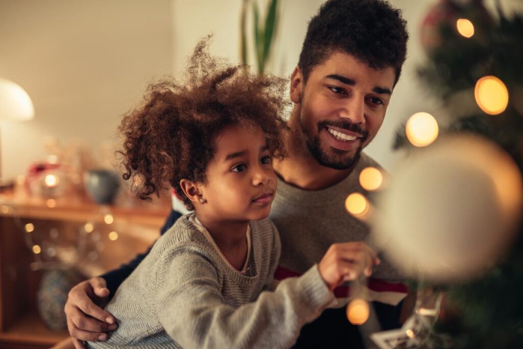 child being held decorating a tree thanks to parent having a sober holiday