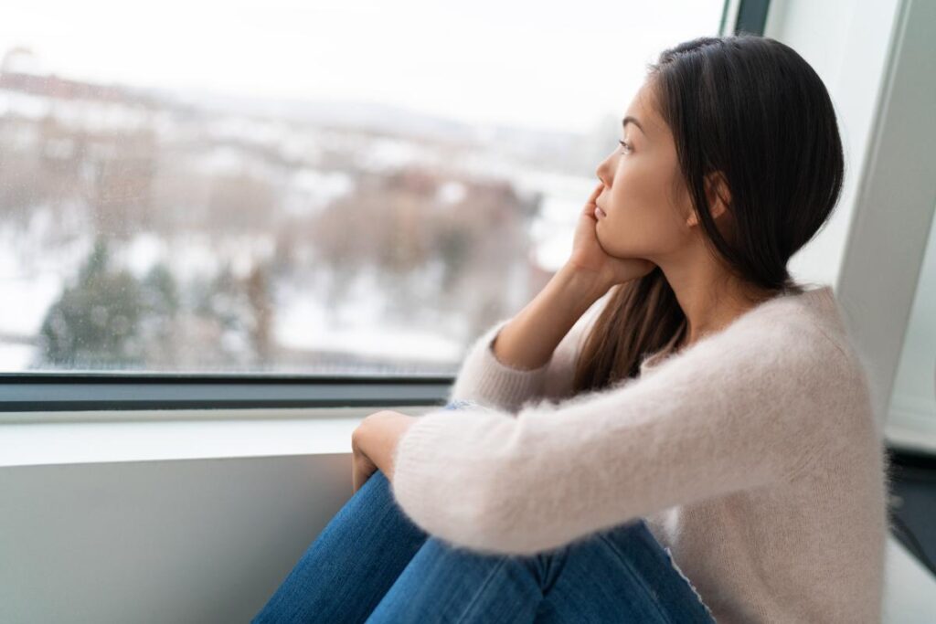 person looking out window wondering is seasonal depression genetic