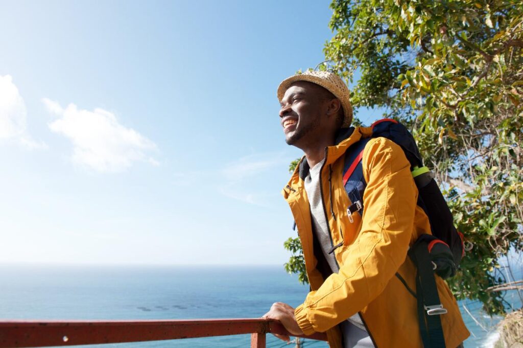 man looking towards the ocean in a yellow jacket