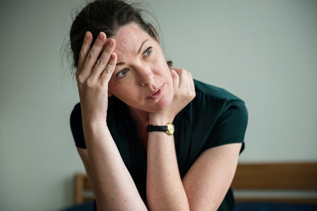 a woman looks nervous and puts her hand on her head wondering do I have social anxiety