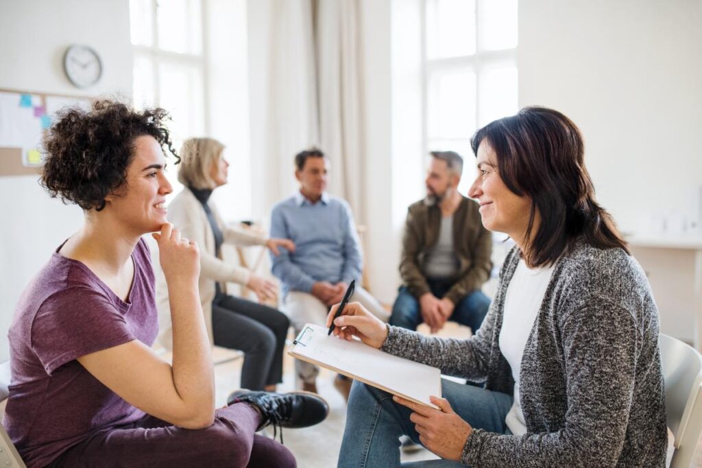 two people talk alone outside of a group possibly using one of many group therapy techniques