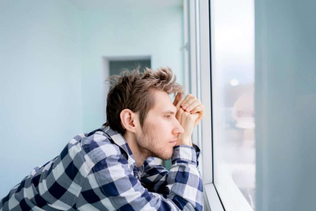 young man staring out the window trying to recall everything you should know about the vivitrol shot