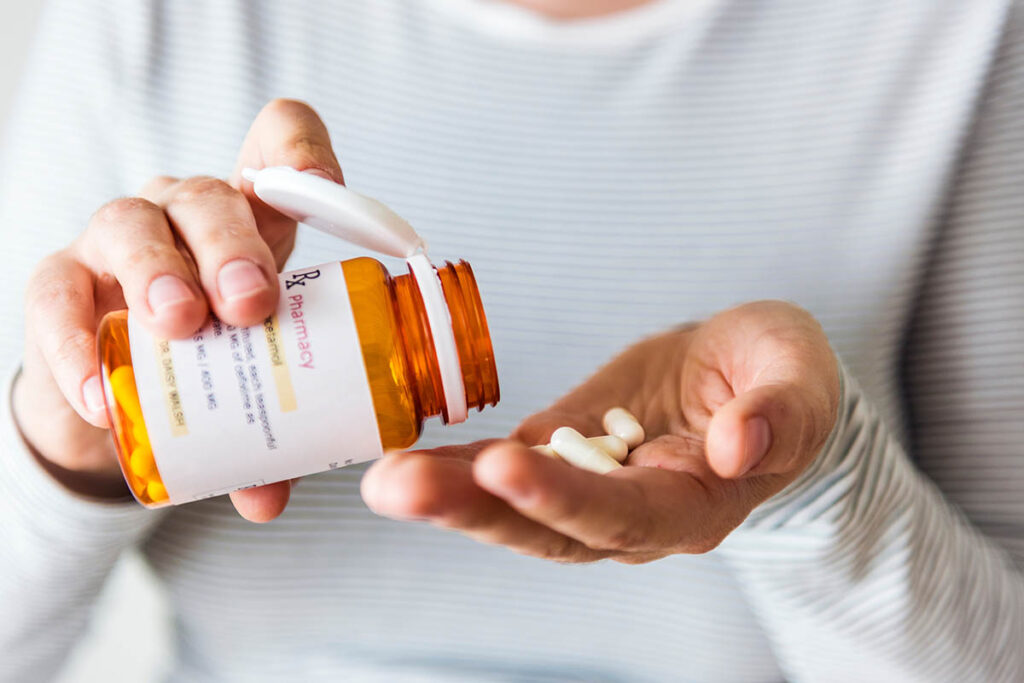 a person holds pills as part of their Pharmacotherapy regimen