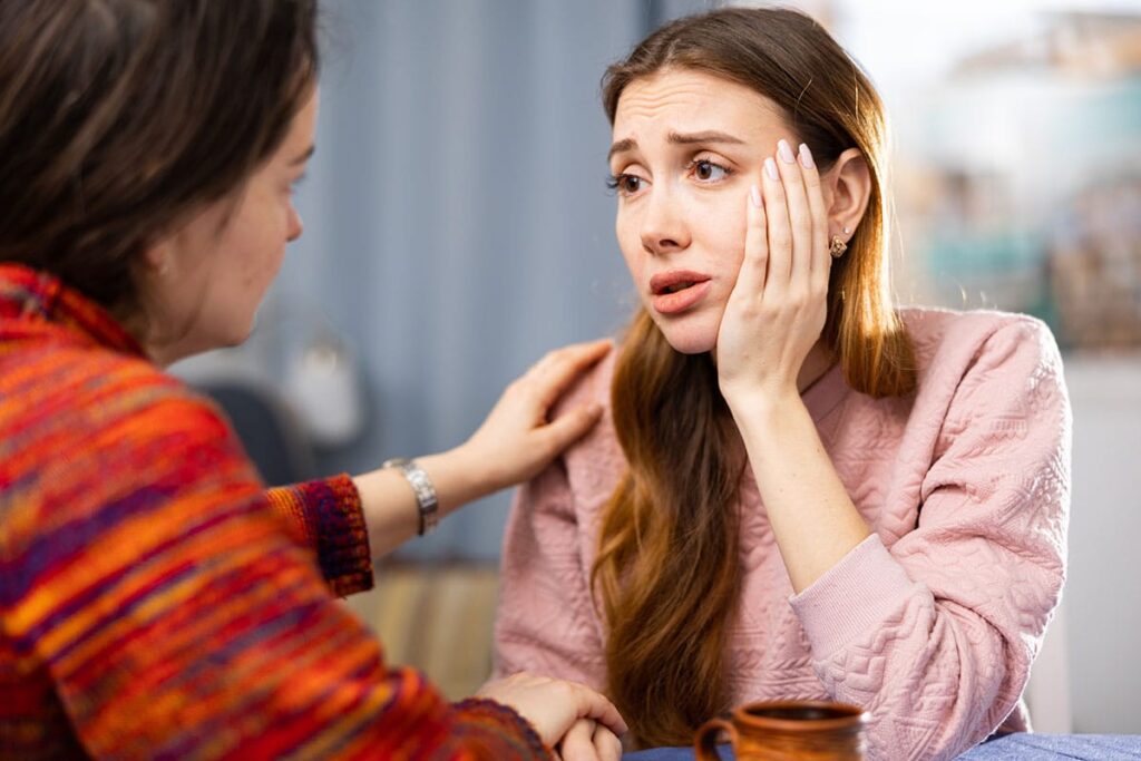 a person comforts an anxious person who has their hand on their cheek as they wonder how long do anxiety disorders last