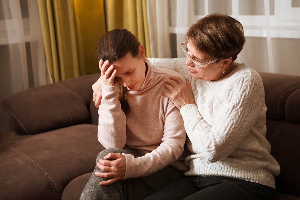 a motherly figure comforts a person who looks distressed as they wonder what causes personality disorder