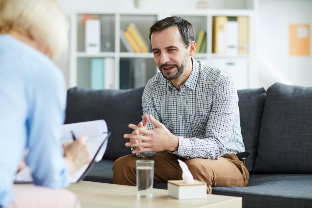 Man sits on couch, asking about dialectical behavior therapy programs