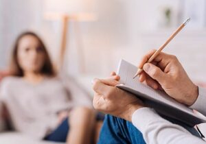 a person sits on the couch out of focus while a therapist does an intake at an alcohol detox center
