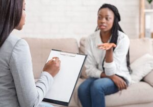 a person sits on a couch and talks to a therapist in Trauma Therapy