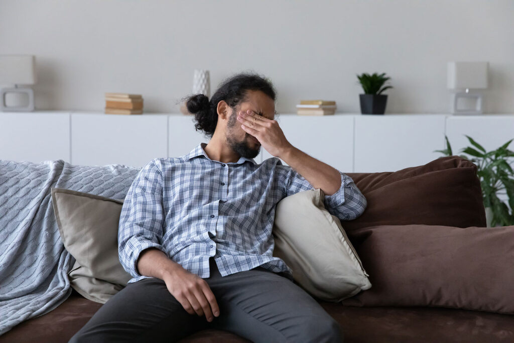 a person looks uncomfortable on a couch while experiencing common withdrawal symptoms