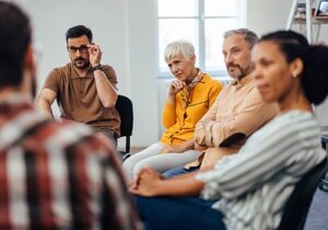 a group of people sit in chairs during a heroin rehab