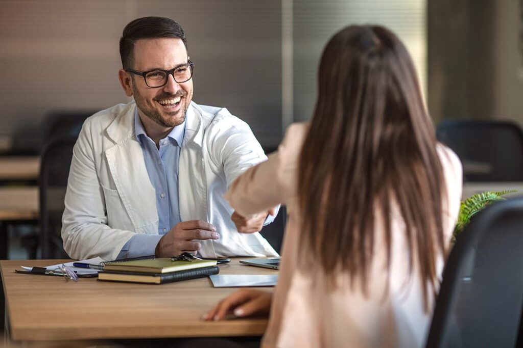 a doctor shakes hands with a patient to show the pros and cons of pharmacotherapy