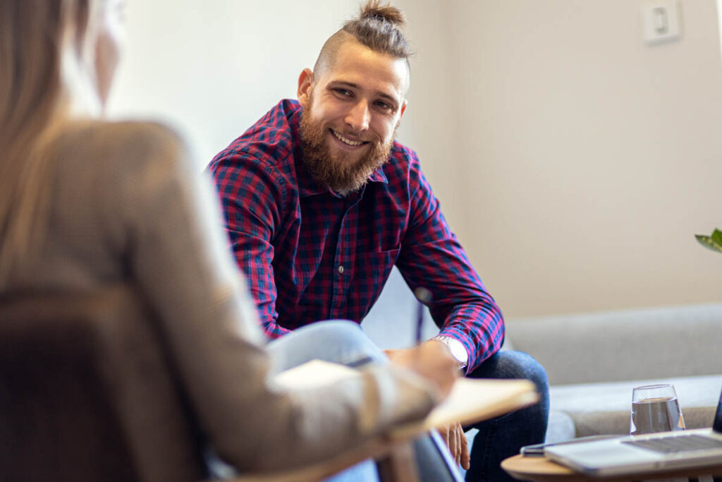 A person smiles at a therapist while enjoying substance abuse treatment benefits