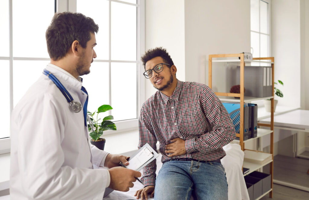 Young man with stomach ache and pain in his right side seeing doctor at hospital